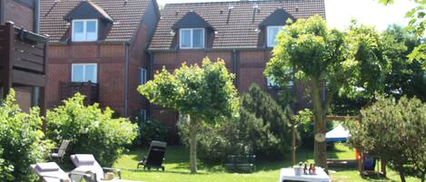 A courtyard with lounge chairs, a picnic table, and a brick building in the background.