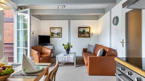 Una sala de estar con un sofá, un televisor, una mesa con un florero y una chimenea.