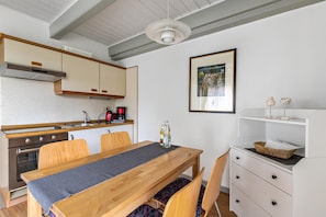 Una cucina moderna con mobili in legno, un piano cottura in acciaio inossidabile e un'area pranzo con tavolo e sedie in legno.