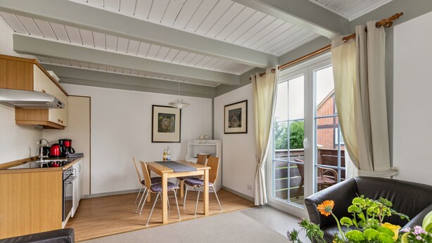 Une cuisine moderne avec un coin repas, un canapé et un balcon agrémenté de rideaux.