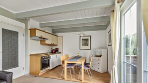 Une cuisine moderne avec des meubles en bois, une table à manger avec des chaises et une grande fenêtre avec des rideaux.