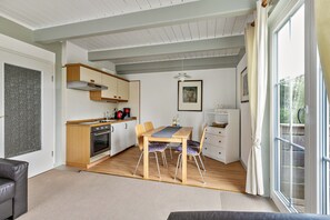 Una cocina moderna con armarios de madera, una mesa de comedor con sillas y un gran ventanal con cortinas.