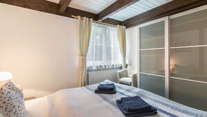 A bedroom with a bed, a chair, a window with curtains, and a sliding glass door. - Apartment 'Atlanta 202' with Private Terrace, Private Garden and Wi-Fi (Pellworm)