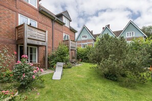 Un quartier résidentiel avec des maisons en briques, une pelouse et un toboggan en bois.