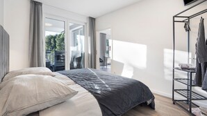 Un dormitorio moderno con cama, televisor, armario y balcón con vistas.