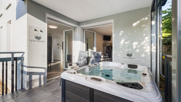 Un jacuzzi en un área exterior cubierta con vistas a un edificio que dice 'EGGE-RESORT'.