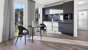 Una cocina moderna con armarios oscuros, horno empotrado y refrigerador.