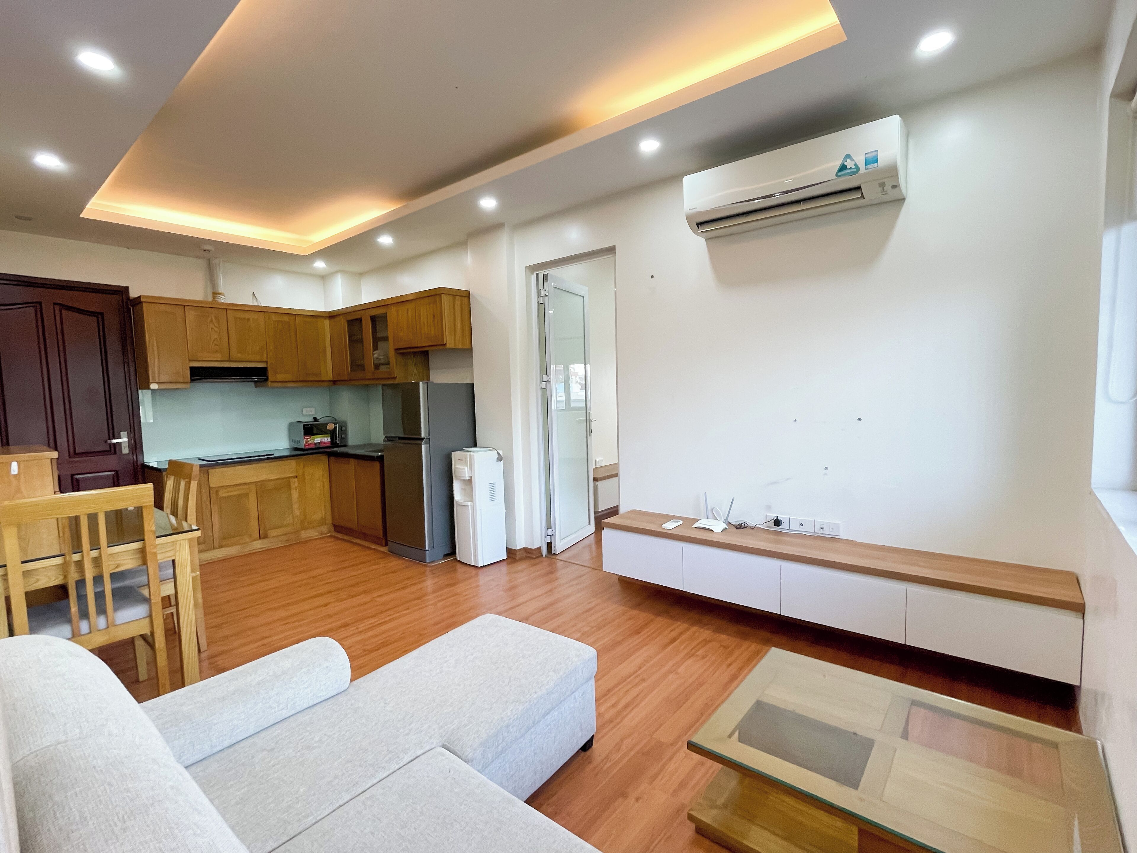 A compact living space with a kitchenette, a sofa, a coffee table, and an air conditioning unit.