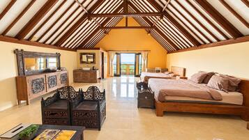 A spacious room with a high ceiling, a large bed, a wooden cabinet, and a dining table.