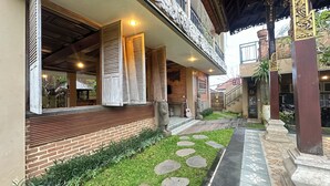 A courtyard with a brick wall, wooden shutters, a statue, and a tiled pathway.