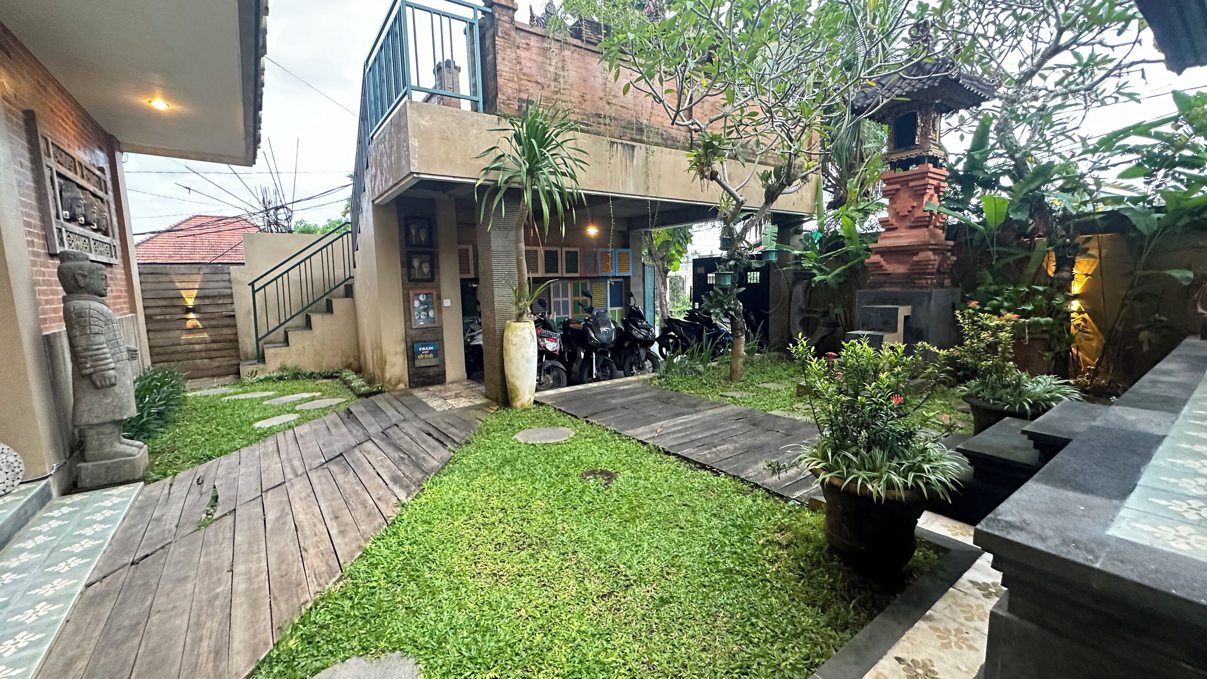 A courtyard with a wooden deck, a statue, and a small garden area.