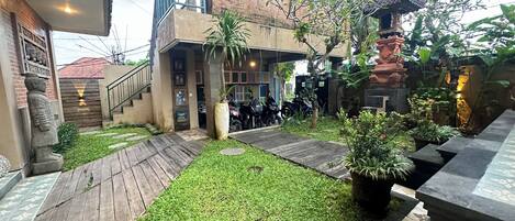 A courtyard with a wooden deck, a statue, and a small garden area.