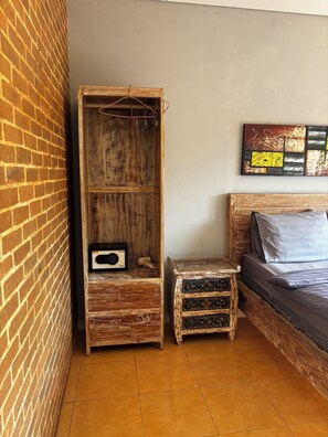 Un dormitorio con una cama, un armario de madera, un taburete pequeño y una obra de arte en la pared.