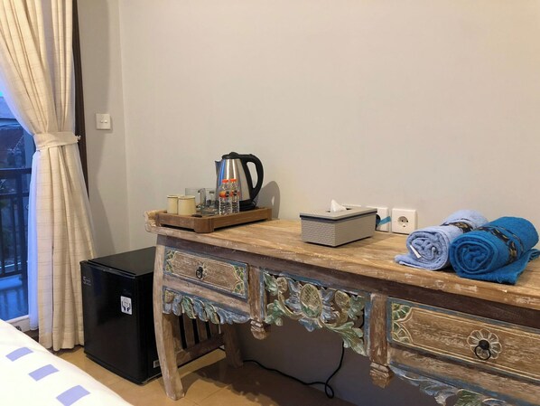 A wooden desk with a kettle, a tissue box, and towels. - Bukawa Lodge Jimbaran (Nusa Dua)