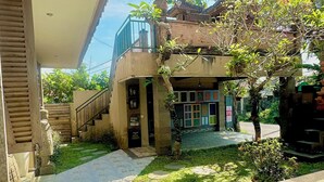 A courtyard with a traditional building, a staircase, and a small garden area with stepping stones.