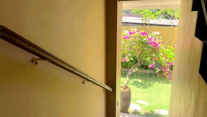 A staircase leading to an outdoor area with a garden and a tree with pink flowers.