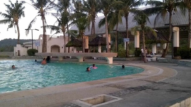 A swimming pool with palm trees and a bridge. - 3G's & C Calapan Transient House (Calapan)