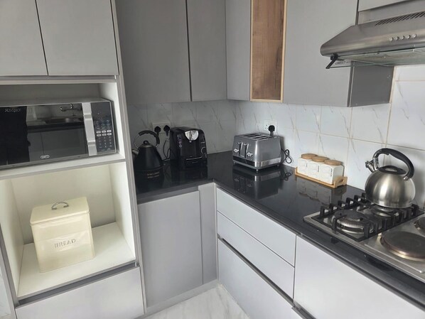 Eine kleine Küche mit Mikrowelle, Toaster, Wasserkocher und einer Brotdose auf der Arbeitsfläche.