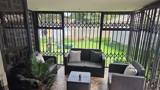 Un balcon avec un canapé, deux fauteuils, une table basse et une plante en pot.