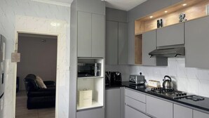 Une cuisine moderne avec des meubles de couleur grise, un plan de travail noir et un four encastré.
