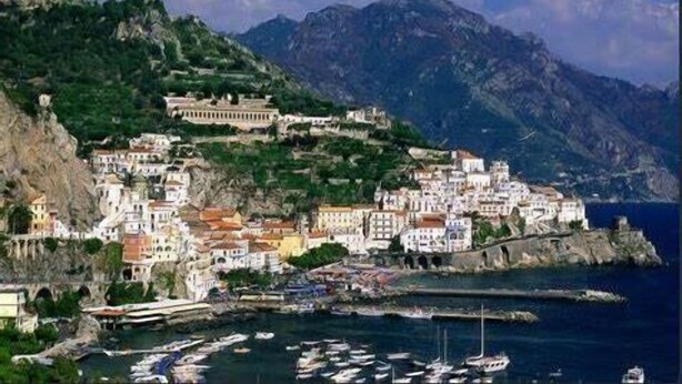 A coastal town with buildings on a hillside, a marina with boats, and mountains in the background. - 1 Bed House - Sleeps 3 - Wifi (Minori)