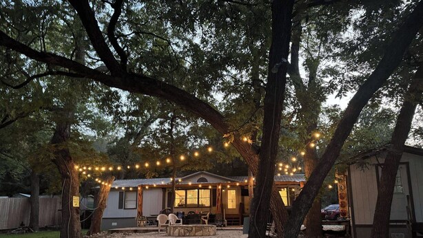 A house with a patio, string lights, and a car parked in the background.