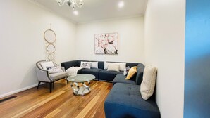 Ein modernes Wohnzimmer mit einem grauen Sofa, einem runden Glastisch und einer Deckenleuchte.