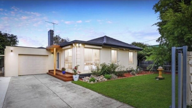 Ein eingeschossiges Haus mit Garage, einer Veranda mit Treppe und einem kleinen Garten mit Hydrant.