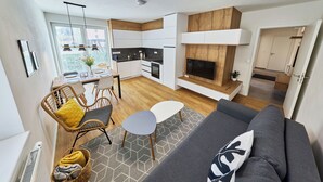 En moderne lejlighed med spiseområde, tekøkken og opholdsstue med sofa og tv.