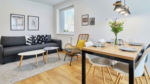 En moderne stue med sofa, sofabord, spisebord, stole og kunst på væggene.