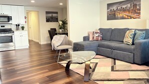 A modern living room with a grey sofa, a glass coffee table, and a patterned rug. - Apartment with excellent location, a few minutes from Manhattan New York (Jersey City)