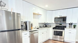 A modern kitchen with white cabinets, stainless steel appliances, and a herringbone wood floor. - Apartment with excellent location, a few minutes from Manhattan New York (Jersey City)