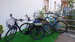 Three bicycles parked against a wall with a green artificial turf in front. - Giardino del Sole (Ascoli Piceno)
