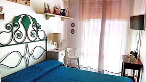 A bedroom with a bed, a desk, a chair, a television, and a window with curtains. - Giardino del Sole (Ascoli Piceno)