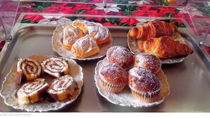 A tray of assorted pastries including croissants and cinnamon rolls, displayed in a clear plastic container. - Giardino del Sole (Ascoli Piceno)