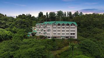 A multi-story hotel with a green roof, surrounded by dense forest.