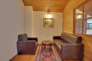 A room with a wooden ceiling, a painting on the wall, a sofa, two armchairs, and a small round table. - KEYS PRIMA BY LEMON TREE HOTELS  (Darjeeling)