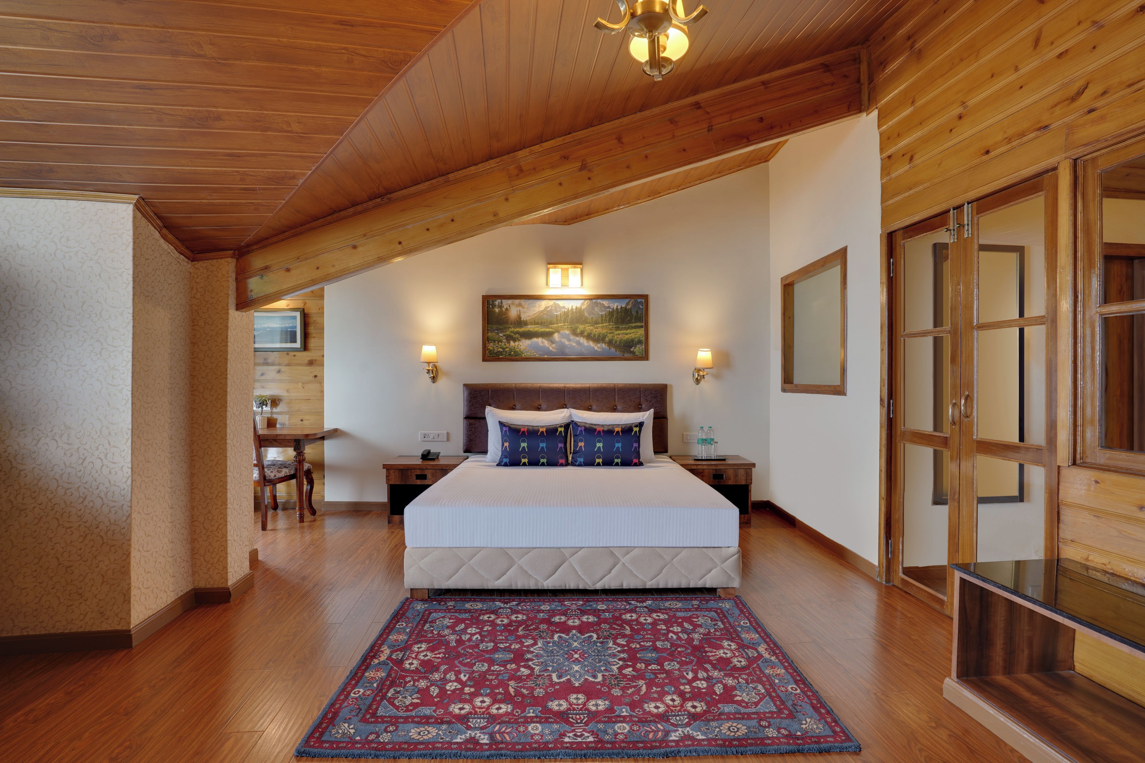 Une chambre à coucher avec un grand lit, un plafond en bois, un tableau au mur et une table de chevet avec une lampe.