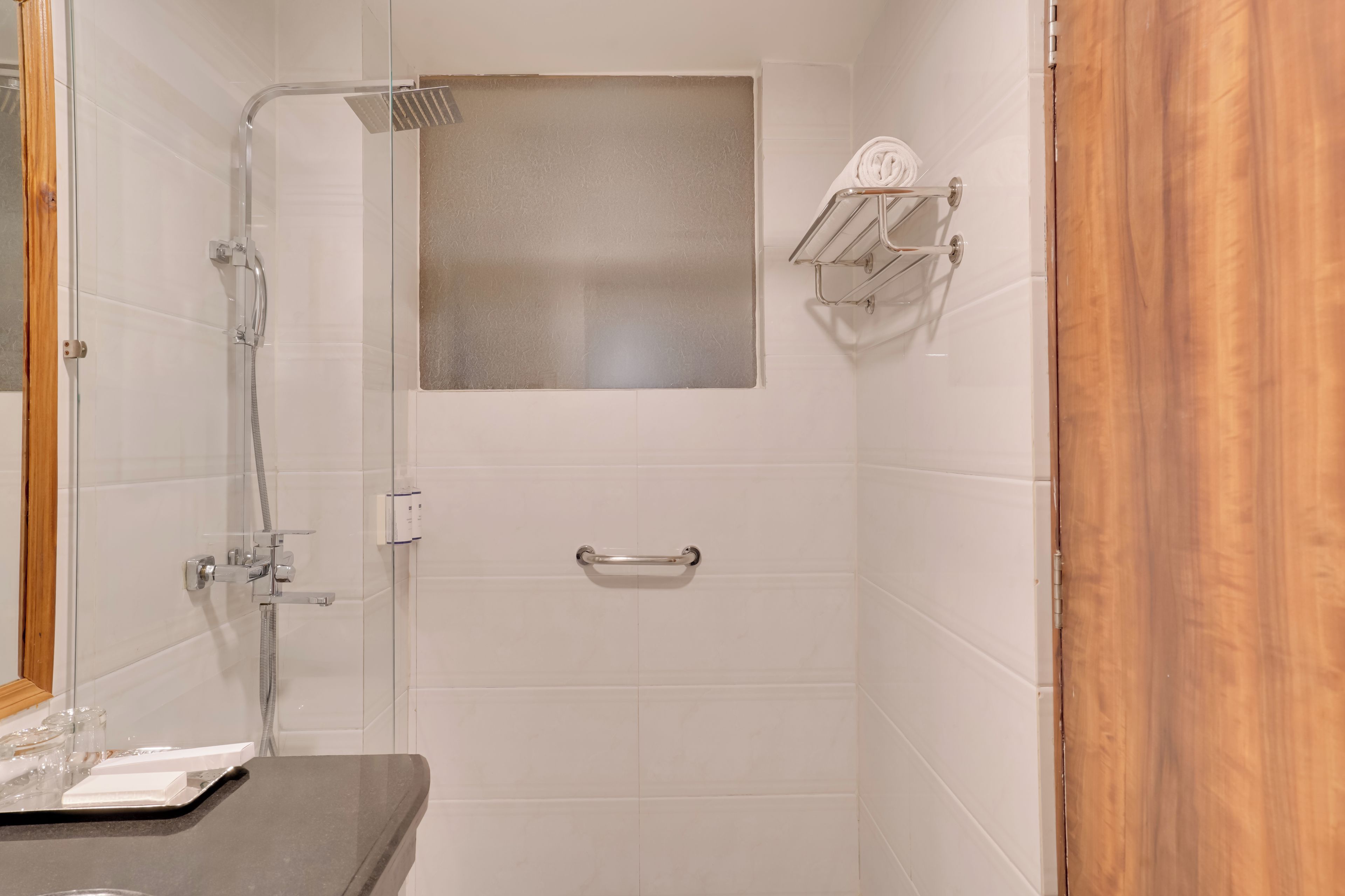 Un baño con cabina de ducha de vidrio, toallero y barra de apoyo.