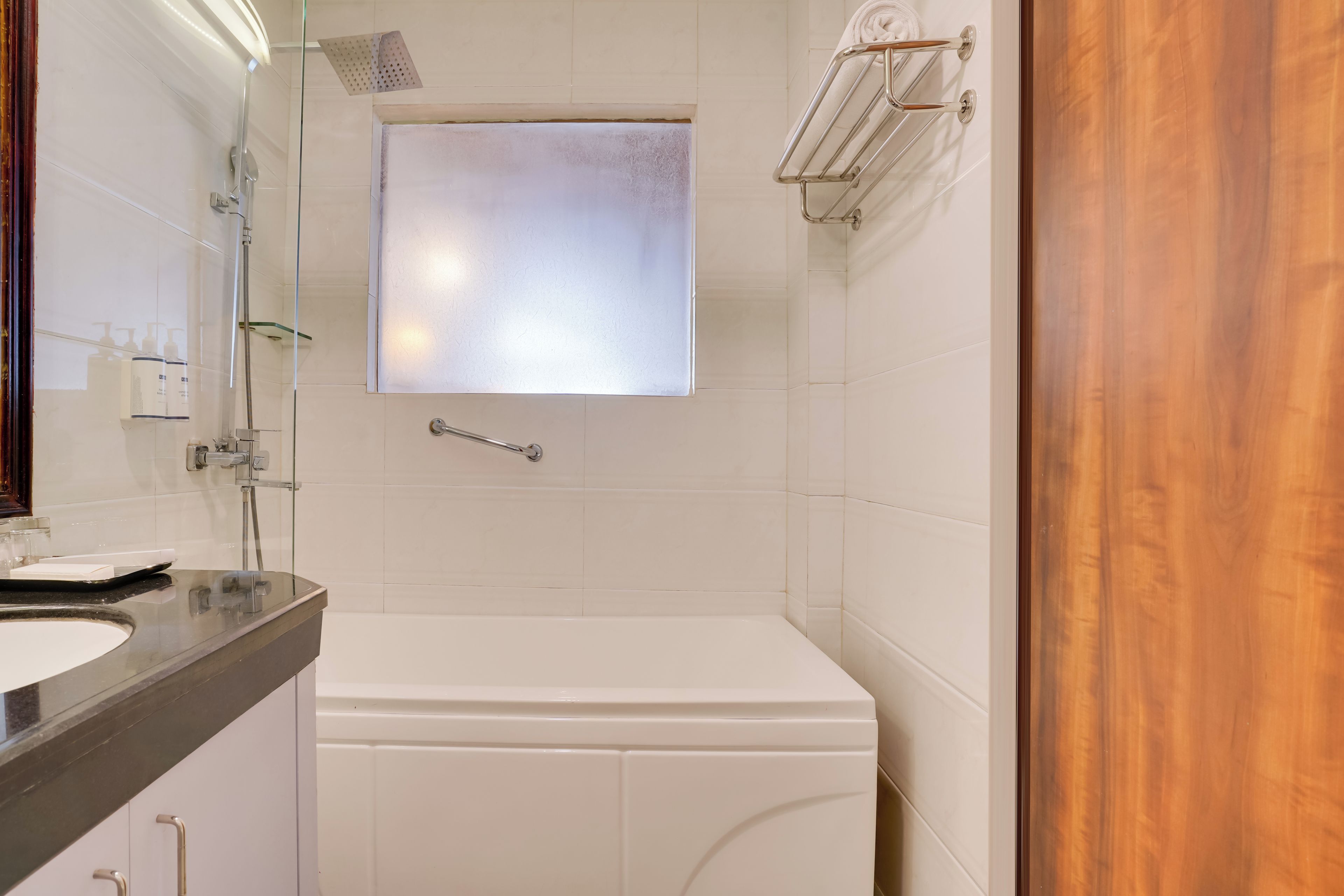 Un baño con una bañera blanca, cabina de ducha de vidrio y puerta de madera.