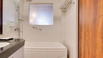 Un baño con una bañera blanca, cabina de ducha de vidrio y puerta de madera.