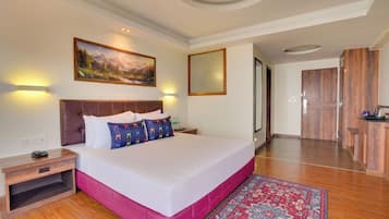 Una habitación de hotel con una cama grande, una mesita de noche, un cuadro y un armario de madera.