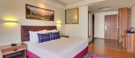 A hotel room with a large bed, a nightstand, a painting, and a wooden wardrobe.