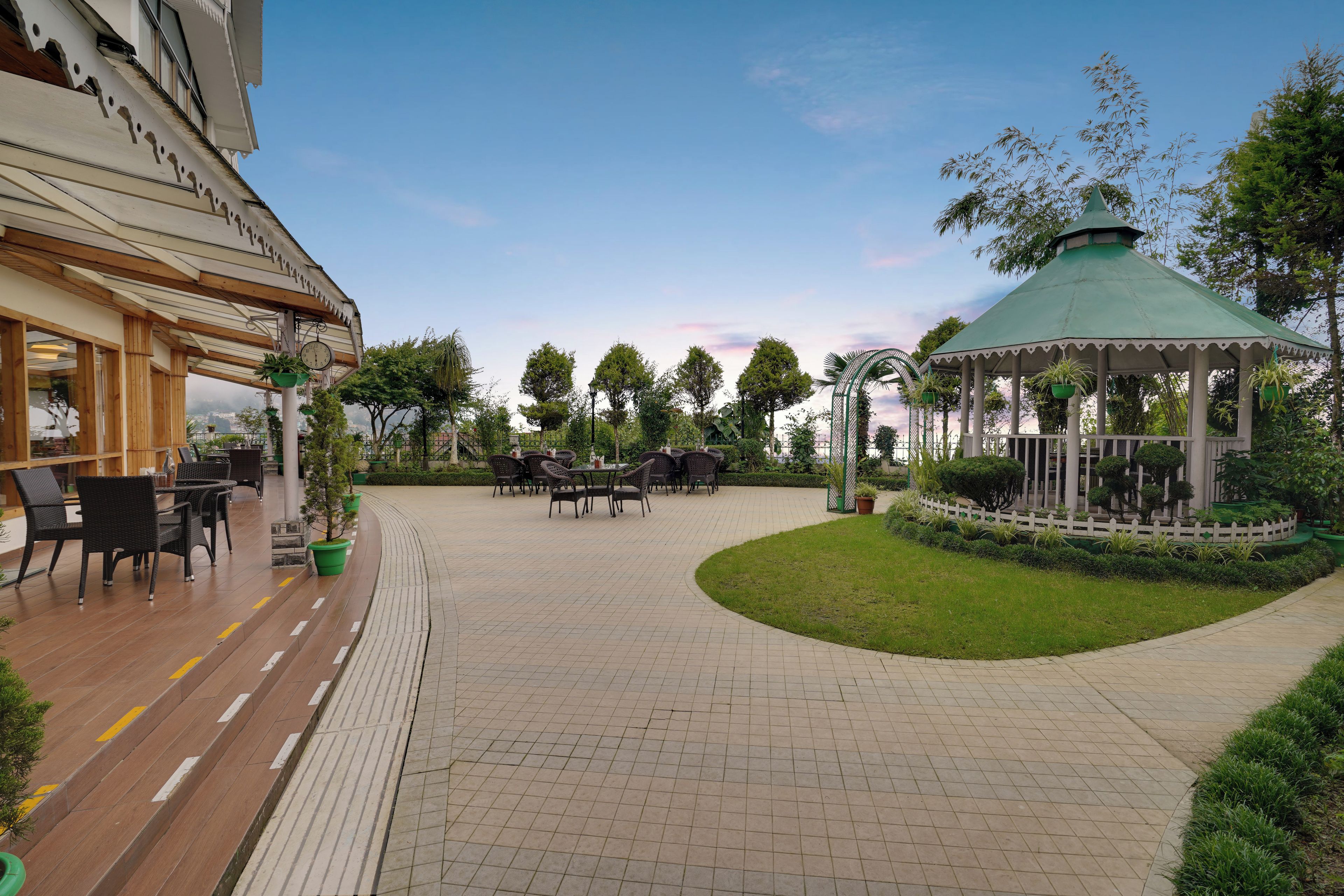An outdoor patio area with tables and chairs, a gazebo, and a view of the cityscape.