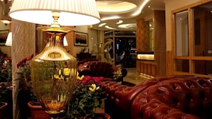 Un hall d’entrée avec un grand lampadaire, des canapés en cuir et des plantes en pot.