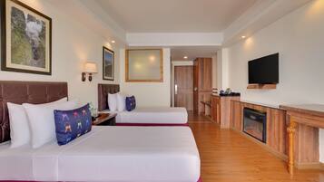 A hotel room with two beds, a TV, a fireplace, and a kitchen area.