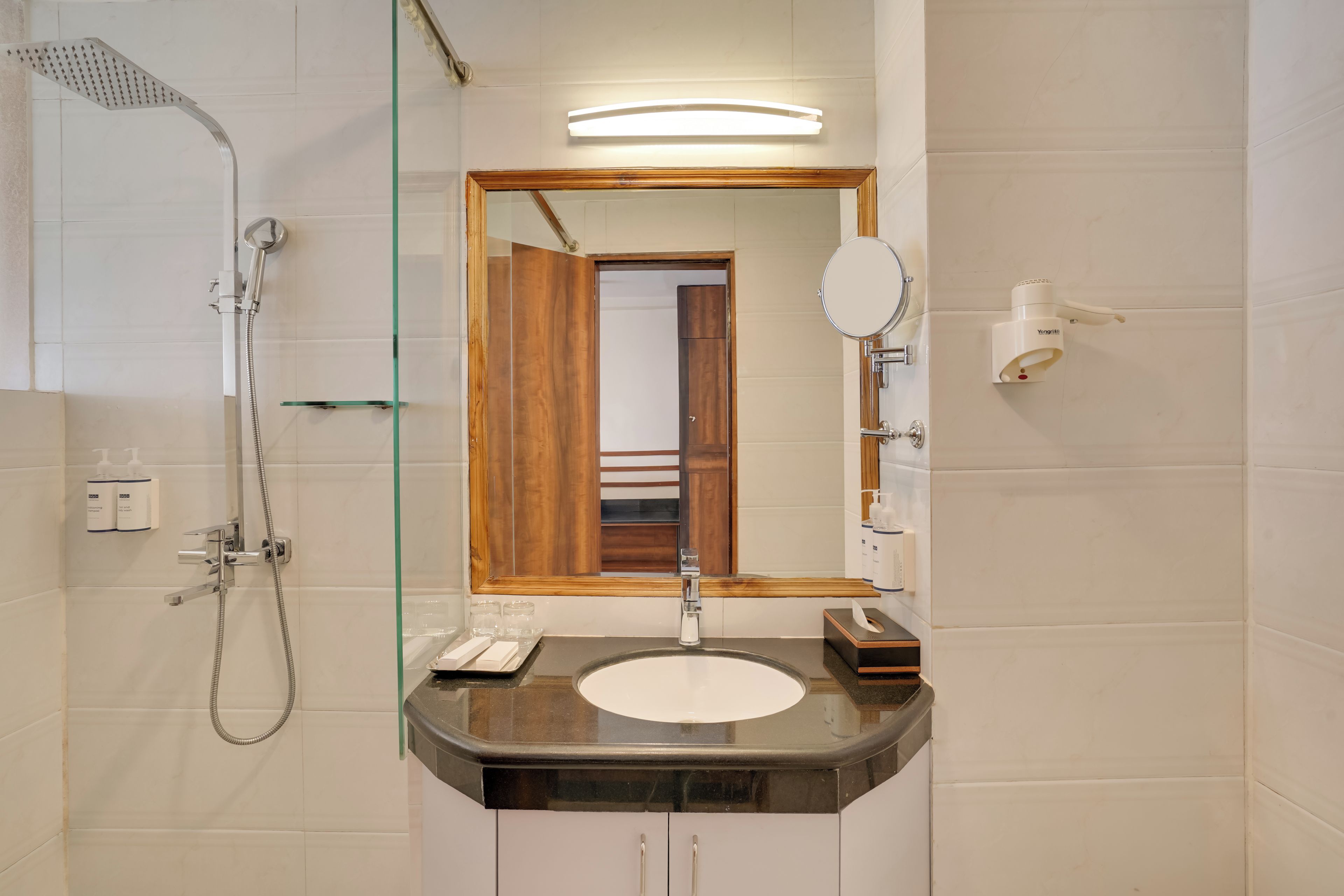 A bathroom with a shower, a sink, a mirror, and a toilet.