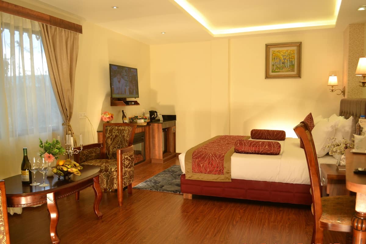 A hotel room with a bed, a desk with a chair, a television, and a painting on the wall.