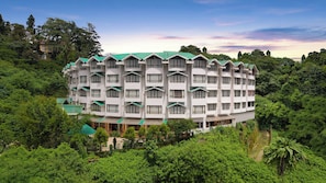A multi-story hotel with a symmetrical facade, surrounded by dense greenery. - KEYS PRIMA BY LEMON TREE HOTELS  (Darjeeling)