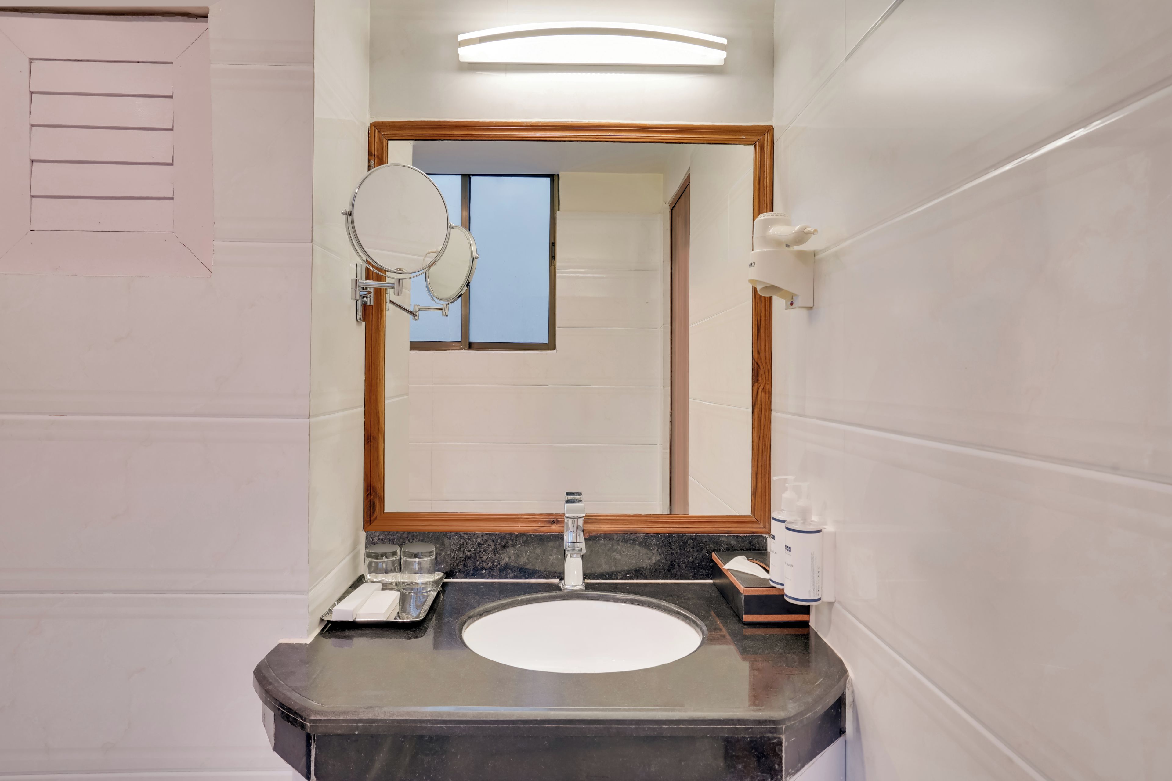 Un baño con un lavabo blanco, un espejo y un dispensador de toallas.